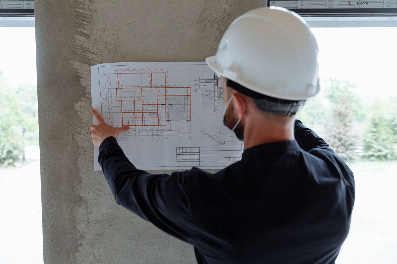 An engineer in a hard hat reading floor plans on site